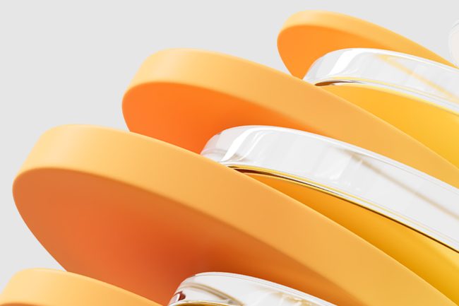 Close-up of overlapping, curved, smooth-edged objects in orange and yellow tones with some transparent sections, set against a plain light gray background.