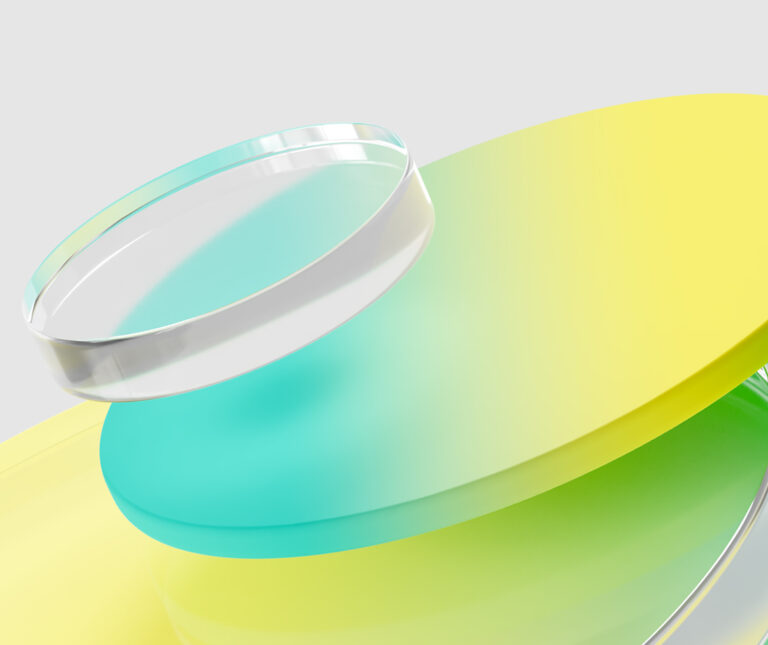 A stack of translucent, circular discs in yellow, green, and blue, topped with a clear cylindrical object, set against a light gray background