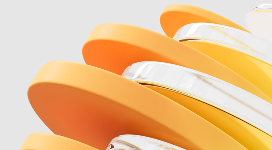 Close-up of overlapping, curved, smooth-edged objects in orange and yellow tones with some transparent sections, set against a plain light gray background.